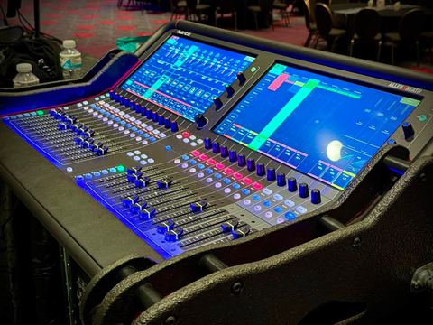 Close-up of a digital mixing console with illuminated faders