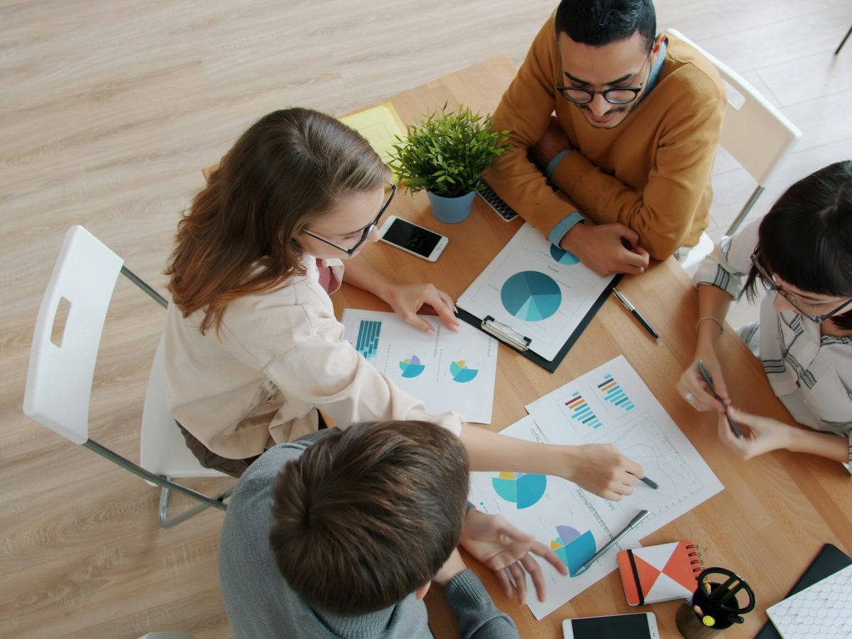 Team collaborating around a table with charts and laptops during an event planning meeting